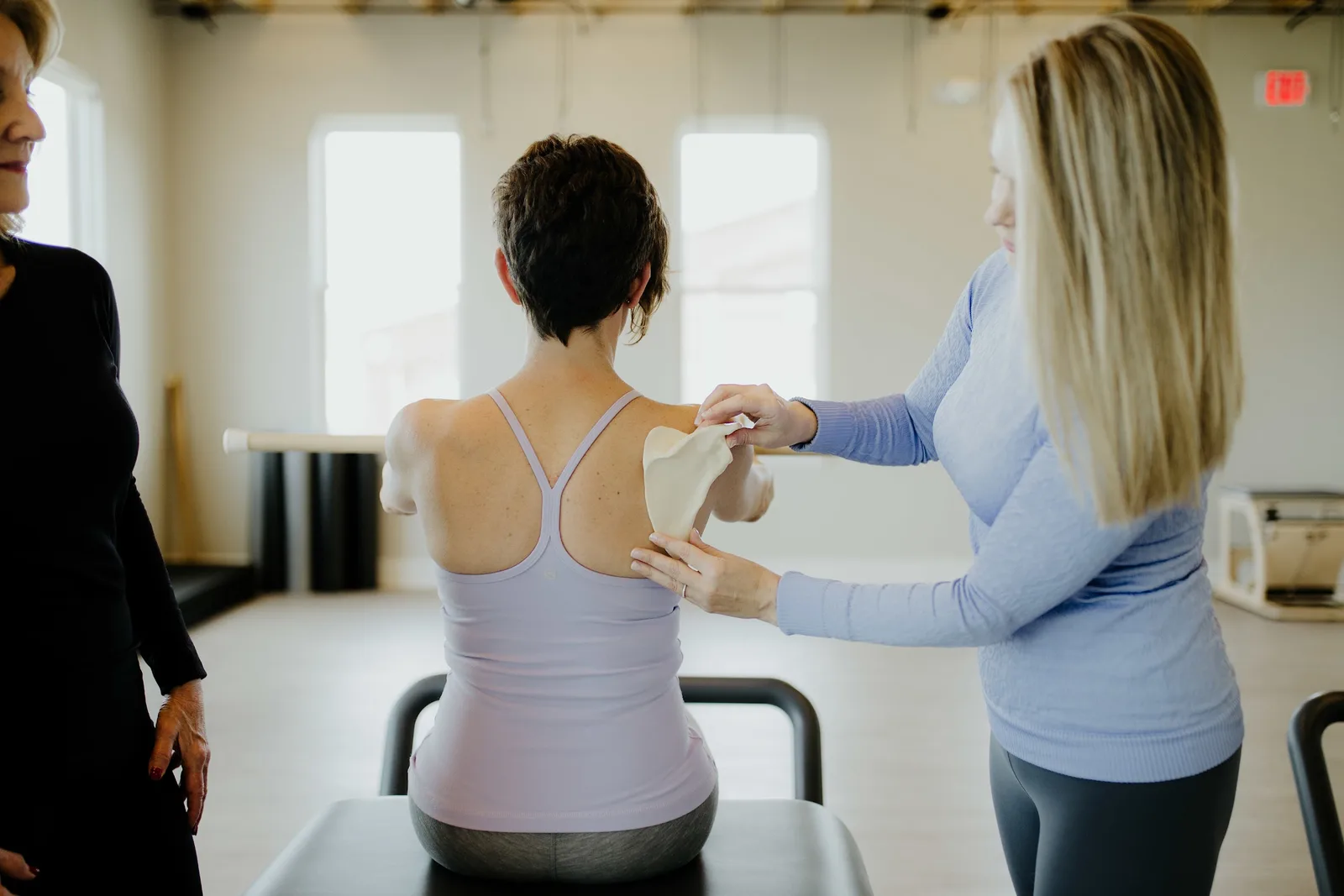 A Bovée Pilates instructor guides a client at the reformer in the bright studio.